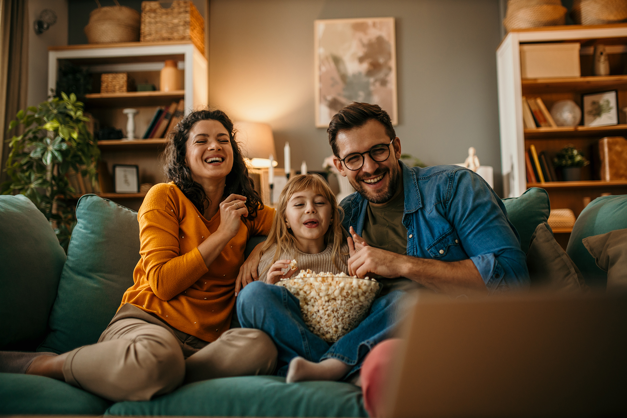 A family of three having a delightful time watching a film and s Shutterstock