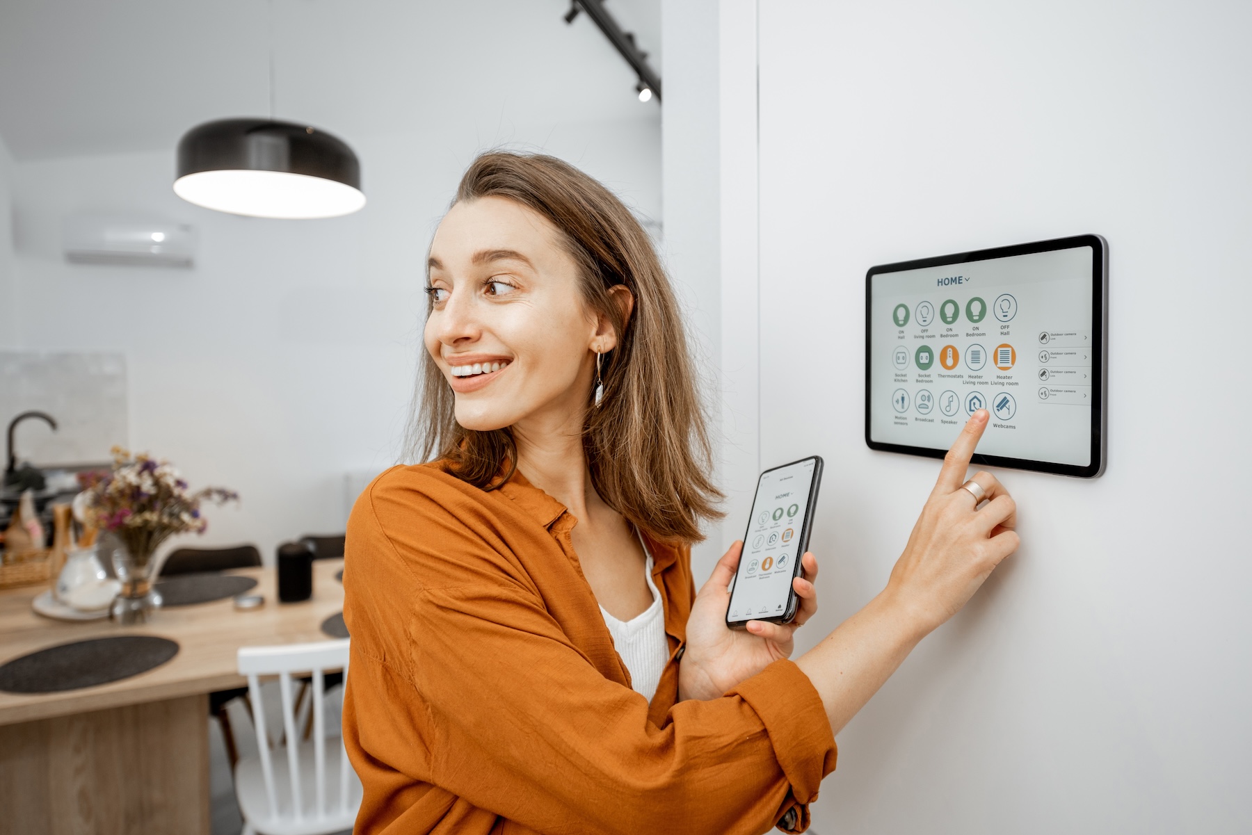 REV Business 2 October Young woman controlling smart home system with a mobile app and digital touch screen panel