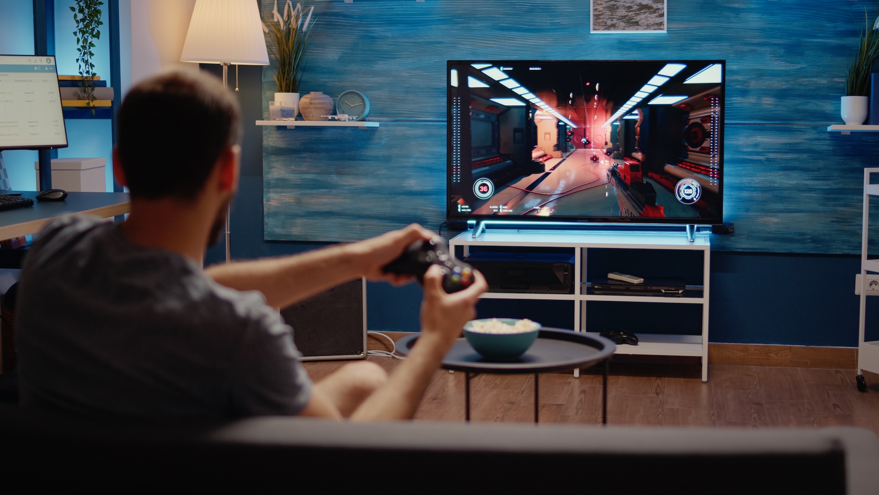 White young man gaming on living room TV and console
