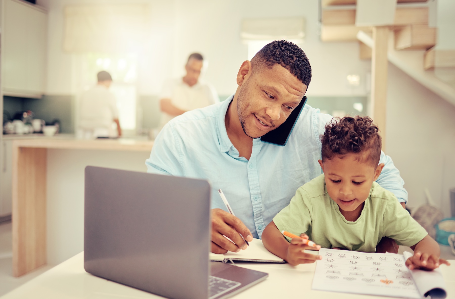 Father working remotely from home, multitasking with his child.