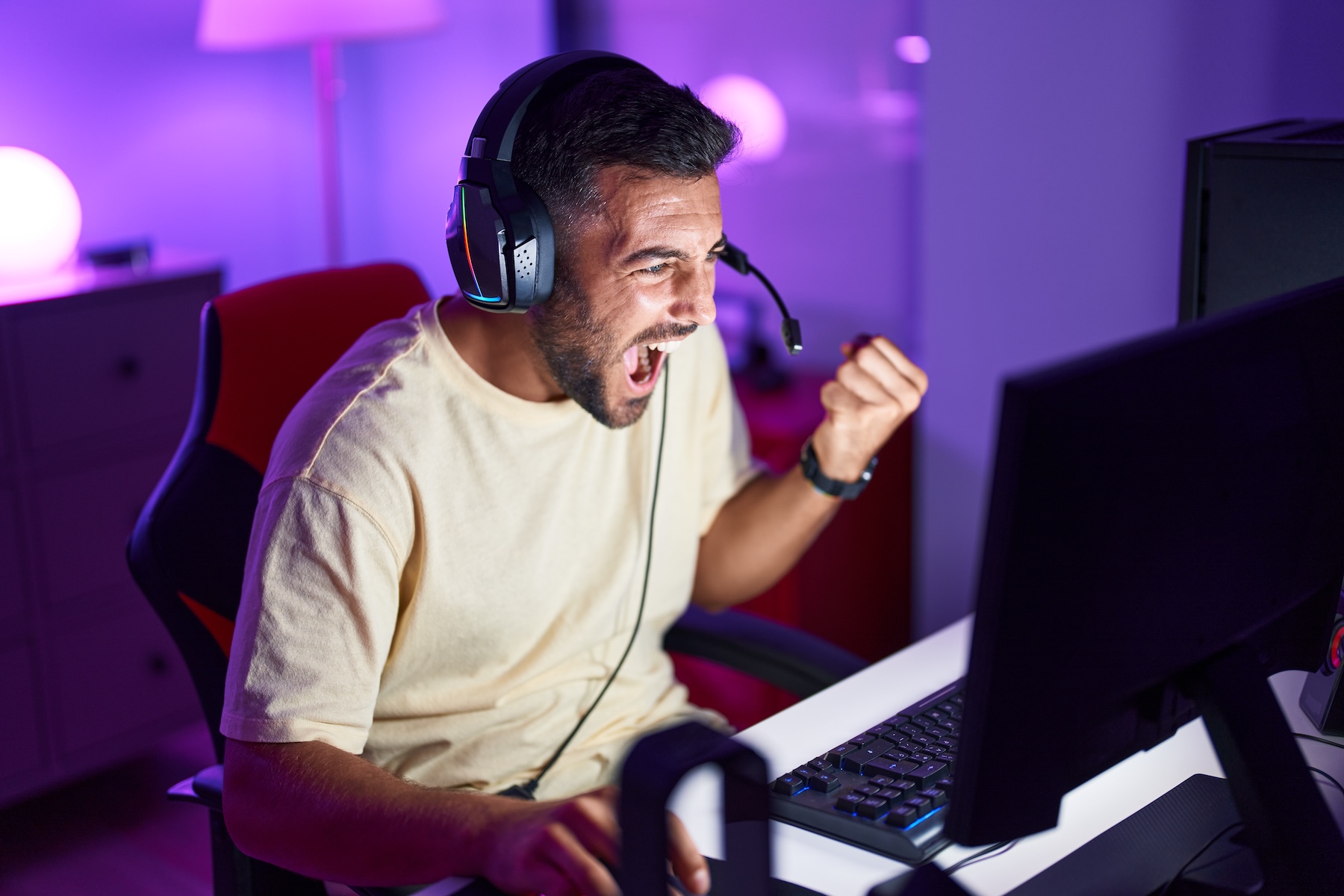 Young man playing video game, cheering at his win