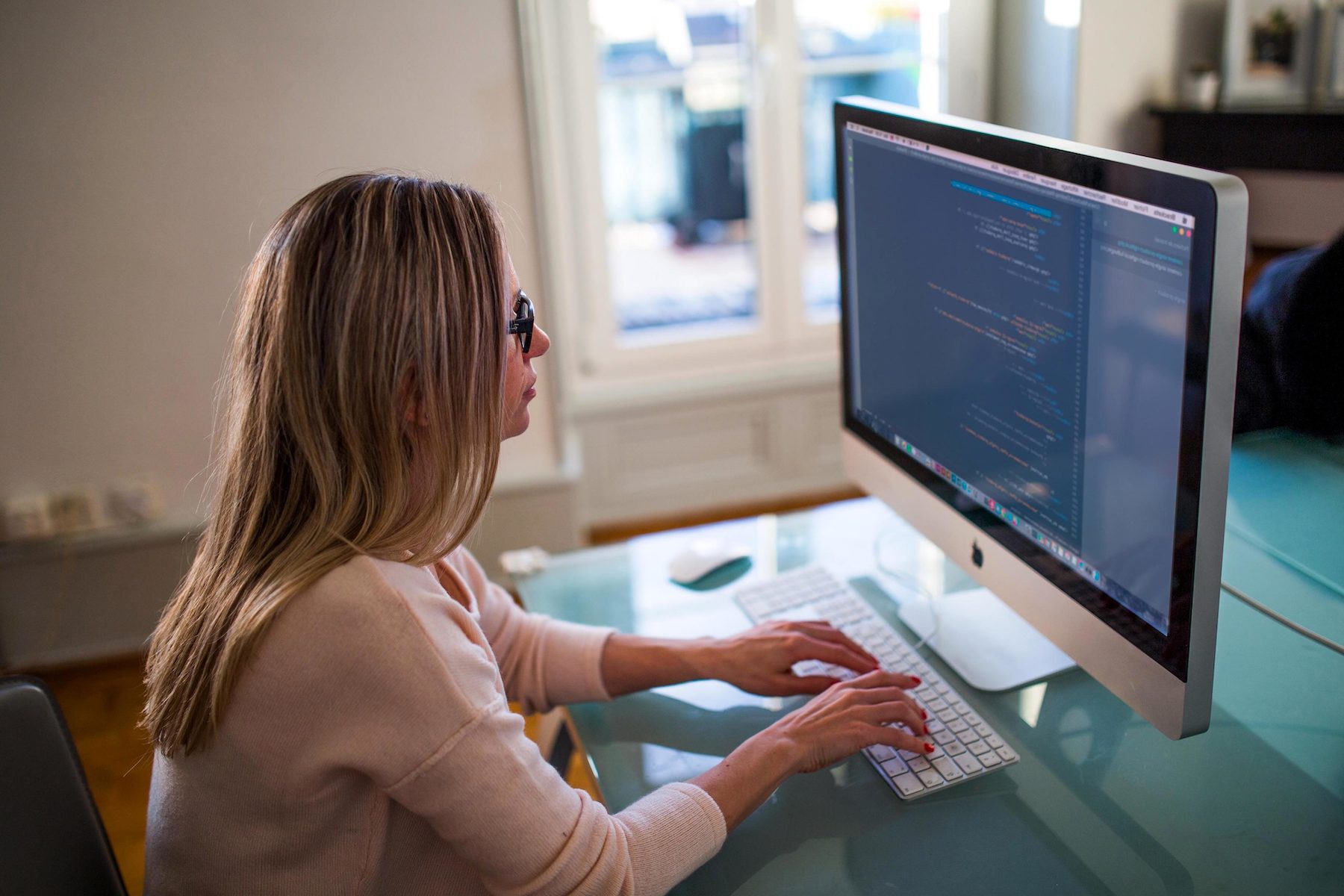 Woman sitting at desk in front of computer typing a blog